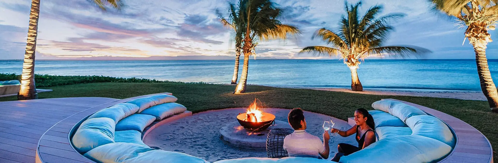 A couple sitting around a boma In Madagascar with palm trees and the ocean in the background | Go2Africa